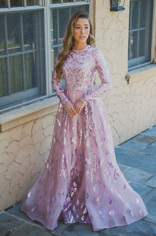  Women wearing mavue modest ball gown with gemoetric shaped sequin designs on the bodice and skirt.