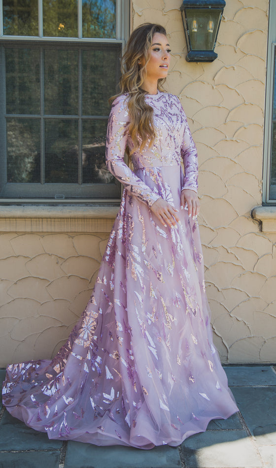 Women wearing mavue modest ball gown with gemoetric shaped sequin designs on the bodice and skirt.