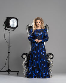 A woman wearing a modest black and cobalt gown with a simple, flattering silhouette made from a shimmering cobalt blue sequin fabric.