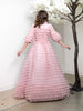 Woman wearing modest blush pink tulle layered ball gown. The bodice is made from a stretch pima and features three-quarter length sleeves and a high collared neck.