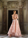 Woman wearing a blush pink modest ball gown with a tiered top and floral ball gown skirt.