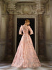 Woman wearing a blush pink modest ball gown with a tiered top and floral ball gown skirt.