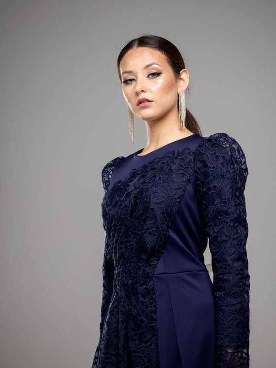 A woman wearing a modest navy blue lace gown with long sleeves.