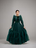 Woman wearing an elegant modest hunter green gown with velvet polka dots, a bottom tier and a green velvet bow at the neck. 