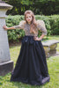 Girl wearing modest black gown with gold top overlay cut from glamorous mini sequin and glitter, and voluminous puffed sleeves. Black feather peplum waist detail.