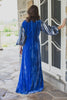 Woman wearing modest cobalt blue crushed velvet ruched gown with straight silhouette and billowy three-quarter length sleeves.