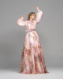  Woman wearing a modest pink floral garden print gown made from silk flowy fabric with a large stretchy buckle mauve belt.